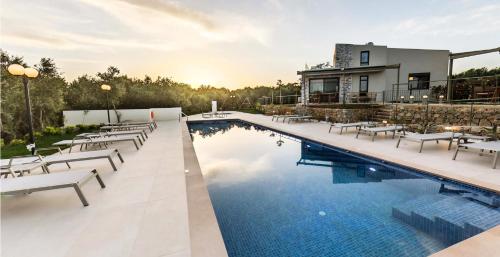 a pool with chairs and a house in the background at Mitos Villas in Gerani