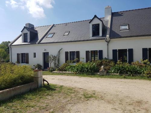 a white house with black windows and a dirt road at Maisons de vacances 4* à Belle ile en Mer, 5 chambres, 2 salles de bains, avec jardins privatifs in Bangor