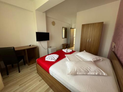 a bedroom with a bed with a red blanket and a desk at Hotel Mihaela in Mamaia
