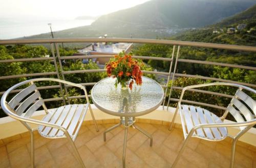 a table with two chairs and a vase of flowers on a balcony at Apartments Vila Emiliano in Borsh