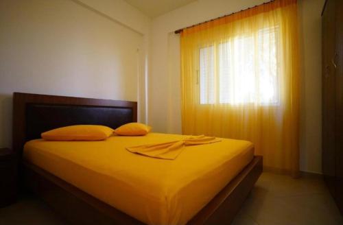 a bedroom with a bed with yellow sheets and a window at Apartments Vila Emiliano in Borsh