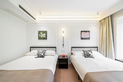 two beds in a room with white walls and windows at Shanghai YD B&B - Yu Garden Bund Store, 400m near Yu Garden subway in Shanghai