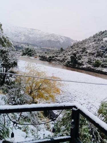 a snow covered view of a river with a bridge at Los queñes Country House in Los Queñes