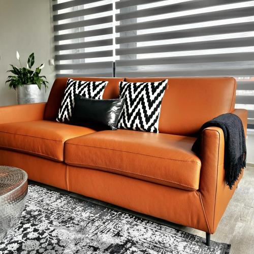 an orange couch with black and white pillows on it at AIMÉE by HOME - boutique apartmán in Jihlava