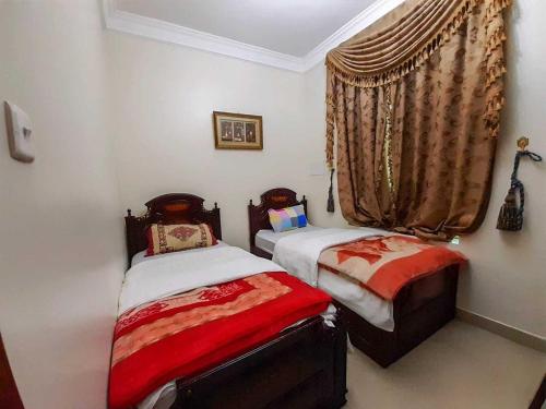 2 camas individuales en una habitación con ventana en fort House en Amán