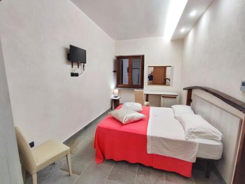 a bedroom with a bed with a red blanket and a chair at Palazzo Iaquinta - Rooms, Restaurant & Wellness in Cicerale