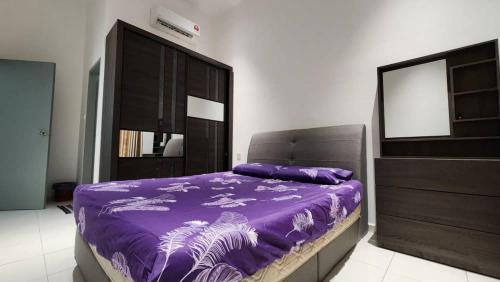 a bedroom with a purple bed and a dresser at Masturi Homestay in Chemor