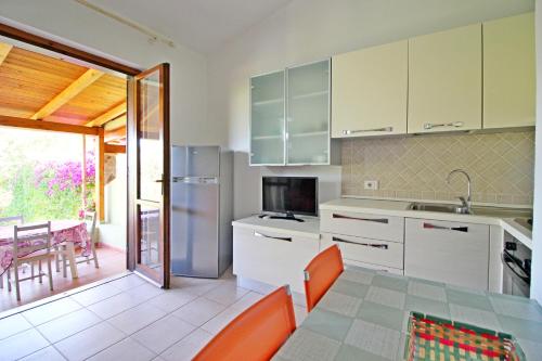 una cocina con armarios blancos y una mesa con sillas naranjas en Bilo Blu Holiday a 80 metri dal mare, en Costa Rei