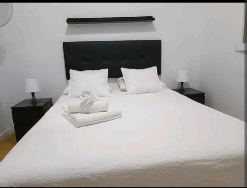 uma grande cama branca com duas mesas de cabeceira e dois candeeiros em cómoda habitación em Madri