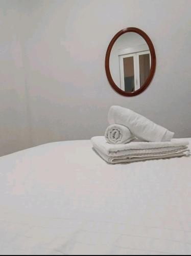 a white bed with a mirror and towels on it at cómoda habitación in Madrid