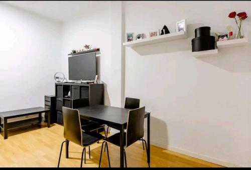 uma sala de jantar com uma mesa preta e cadeiras em cómoda habitación em Madri