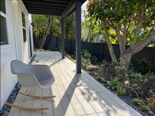 a white chair sitting on a patio next to a house at New Listing -Luxury House on the Riviera , Modern Design, and Panoramic Ocean -30 day Minimum in Santa Barbara