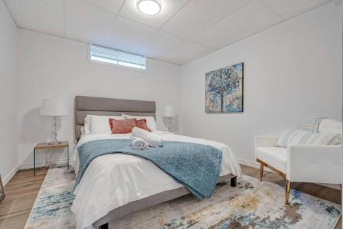 a white bedroom with a bed and a chair at Riviera Escape on Waterfront with Hot Tub in Gatineau