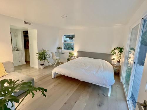 a bedroom with a white bed and a table and chairs at New Listing -Luxury House on the Riviera , Modern Design, and Panoramic Ocean -30 day Minimum in Santa Barbara