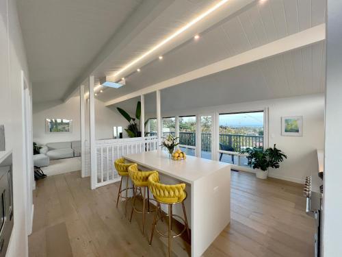 una cocina con una isla blanca y taburetes amarillos en New Listing -Luxury House on the Riviera , Modern Design, and Panoramic Ocean -30 day Minimum, en Santa Bárbara