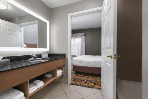 a bathroom with a sink and a mirror and a bed at La Quinta by Wyndham Belton - Temple South in Belton