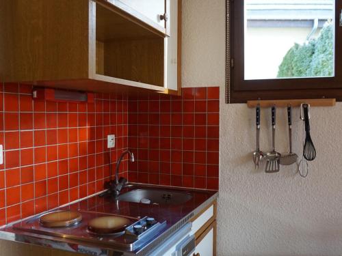 奧特朗的住宿－Studio Autrans-Méaudre en Vercors-Autrans, 1 pièce, 4 personnes - FR-1-737-53，一间带水槽和红色瓷砖墙的厨房