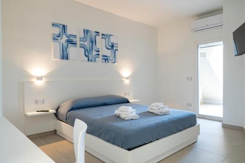 a white bedroom with a bed with towels on it at Su Mari Rooms in Villasimius