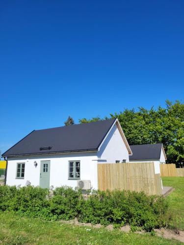 a white house with a black roof at Litet hus i mysig by nära havet in Ystad