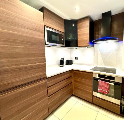 a kitchen with wooden cabinets and a microwave at The Kings Palace Central London by Wild in London