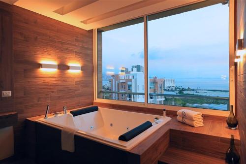 uma grande casa de banho com banheira e uma grande janela em Ibiza Hotel em Jounieh