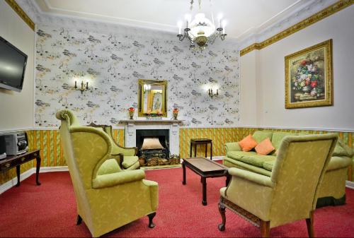 a living room with two chairs and a fireplace at Hotel Garden in Bolesławiec