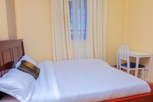 a bed in a bedroom with a table and a chair at EDD'S HOME AWAY FROM HOME in Kisii