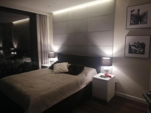 a bedroom with a bed with two lights on it at YOUR Apartment Unia Art Residence in Lublin