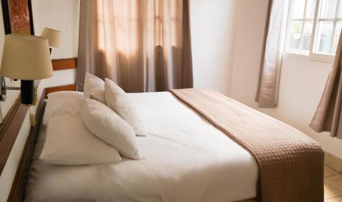 a bedroom with a bed with white sheets and pillows at Hotel Casa Amelia in Flores