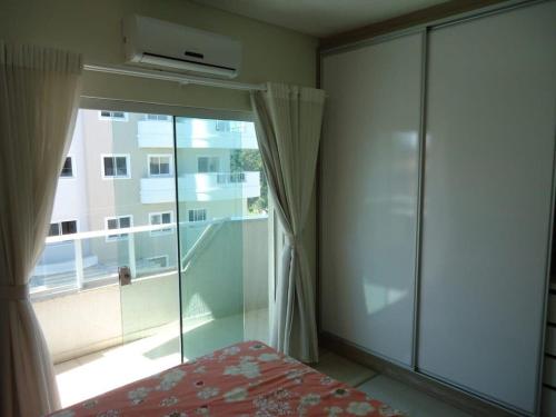 Schlafzimmer mit einer großen Glastür und einem Fenster in der Unterkunft A15 - APARTAMENTO 2 DORMITÓRIOS NO CENTRO DE BOMBINHAS ALUGUEL DE TEMPORADA in Bombinhas