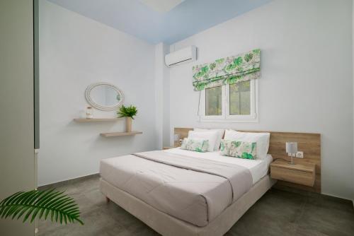 ein weißes Schlafzimmer mit einem Bett und einem Fenster in der Unterkunft Votsalo Blue in Ierápetra