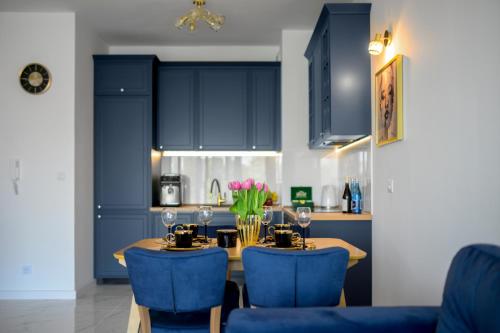 eine Küche mit blauen Schränken sowie einem Tisch und Stühlen in der Unterkunft Apartament Sonata in Zielona Góra