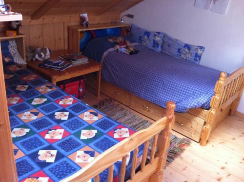 1 dormitorio con 2 camas y mesa en Appartamento Ivo en Campitello di Fassa