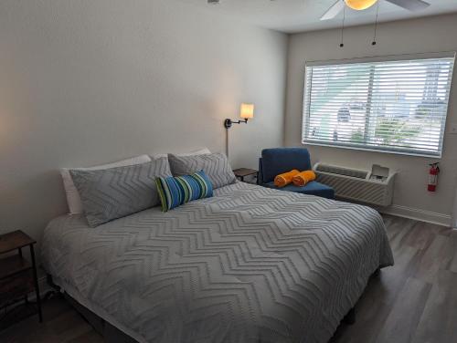 a bedroom with a bed and a window and a chair at The Pointe at Daytona Beach Shores in Daytona Beach Shores