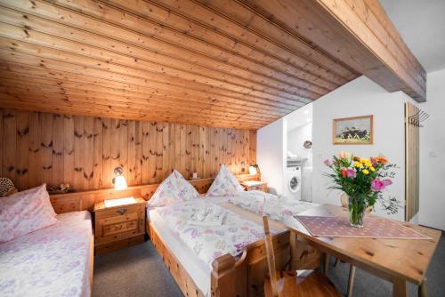 un dormitorio con 2 camas y una mesa con un jarrón de flores en Appartement Gimpl, en Fusch an der Glocknerstrasse