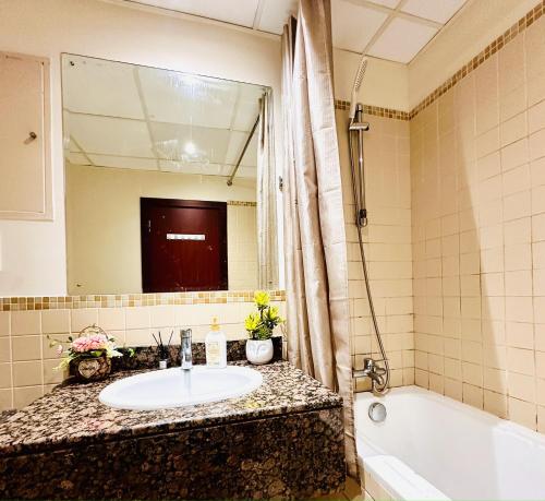 een badkamer met een wastafel, een bad en een spiegel bij The Aero Hostel in Dubai