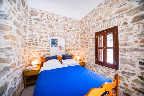 a bedroom with a blue bed in a stone wall at Villa See the Sea in Symi