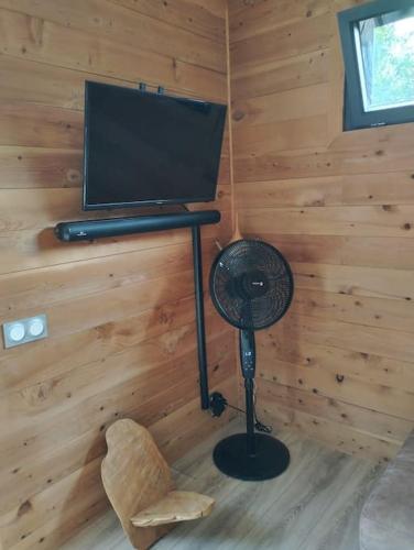 a room with a desk with a fan and a television at Chalet moderne, Jacuzzi & Cinéma in Saint-Coulitz