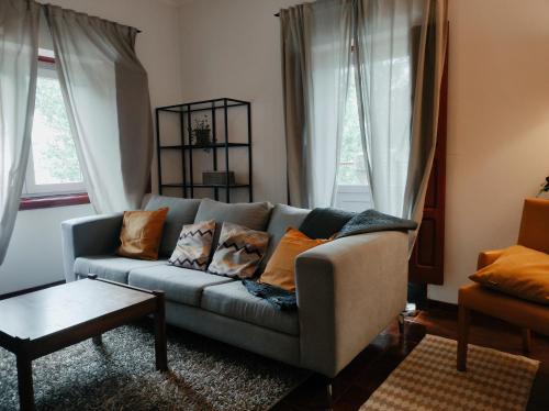 un soggiorno con un divano e due finestre di Casa das Essências, Quinta de Santo António a Covilhã