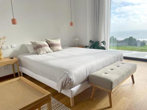 a bedroom with a large white bed with a large window at Casa da Serra in Buarcos