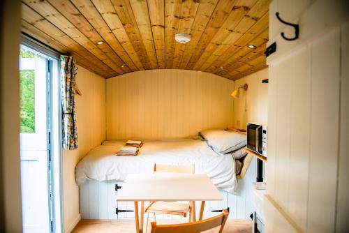 a small room with two beds and a table at Cosy Shepherd's Hut with Hot Tub in Church Stretton