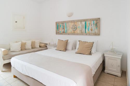 a white bedroom with a large bed and a couch at Rhenia Hotel in Tourlos