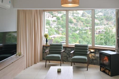 a living room with two chairs and a fireplace at Oikou Thea Guesthouse in Oikos