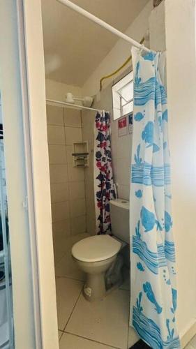a bathroom with a toilet and a shower curtain at Kitnet Mobiliada itapua Vila Velha in Vila Velha