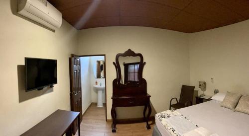 um quarto com um espelho, uma cama e uma televisão em Hostal DEYLUWIN em Juayúa