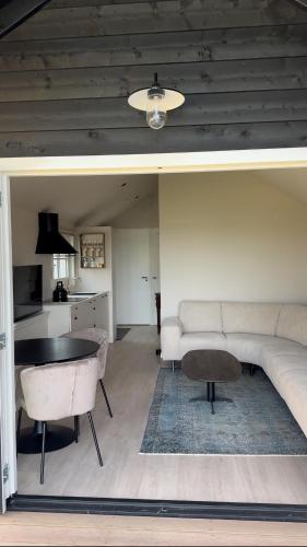 a living room with a couch and a table at HAVENZICHT HUISJE, chique ingericht, compleet uitgerust, prachtig uitzicht! in Belt-Schutsloot