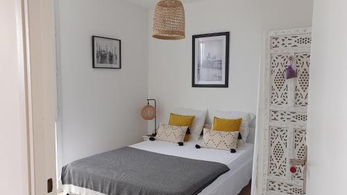 um pequeno quarto com uma cama com almofadas amarelas em Le Doux voyage T3, vue Mer, Wi Fi, PARKING gratuit em Toulon