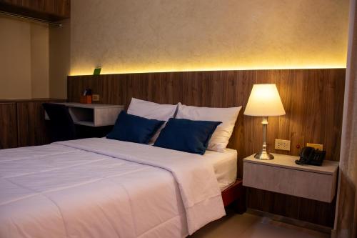 sypialnia z łóżkiem z niebieskimi poduszkami i lampą w obiekcie Hotel America Chiclayo w mieście Chiclayo
