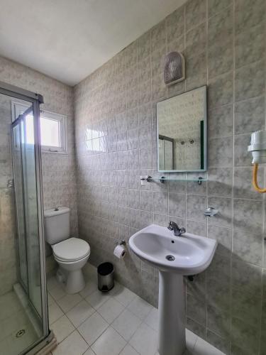 a bathroom with a sink and a toilet and a mirror at Fora Apart Otel Cesme in Çeşme