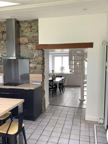 a kitchen with tables and chairs and a stone wall at Le petit Four Neuf in Lézardrieux